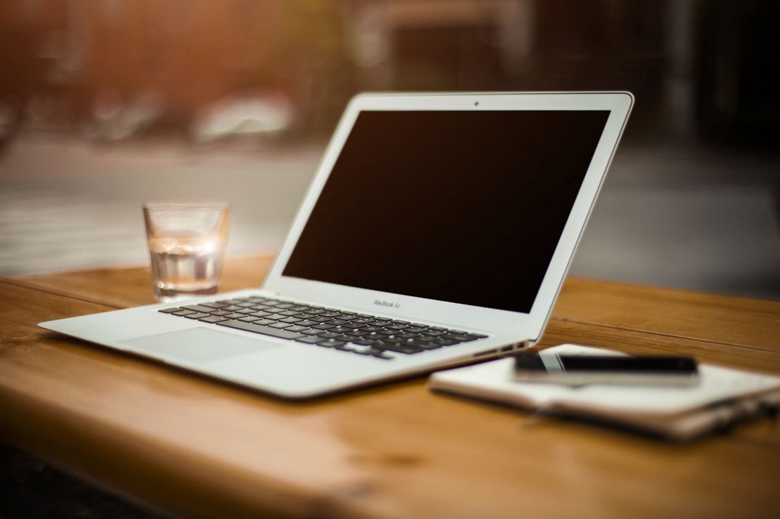 a white laptop sitting on a wooden desk